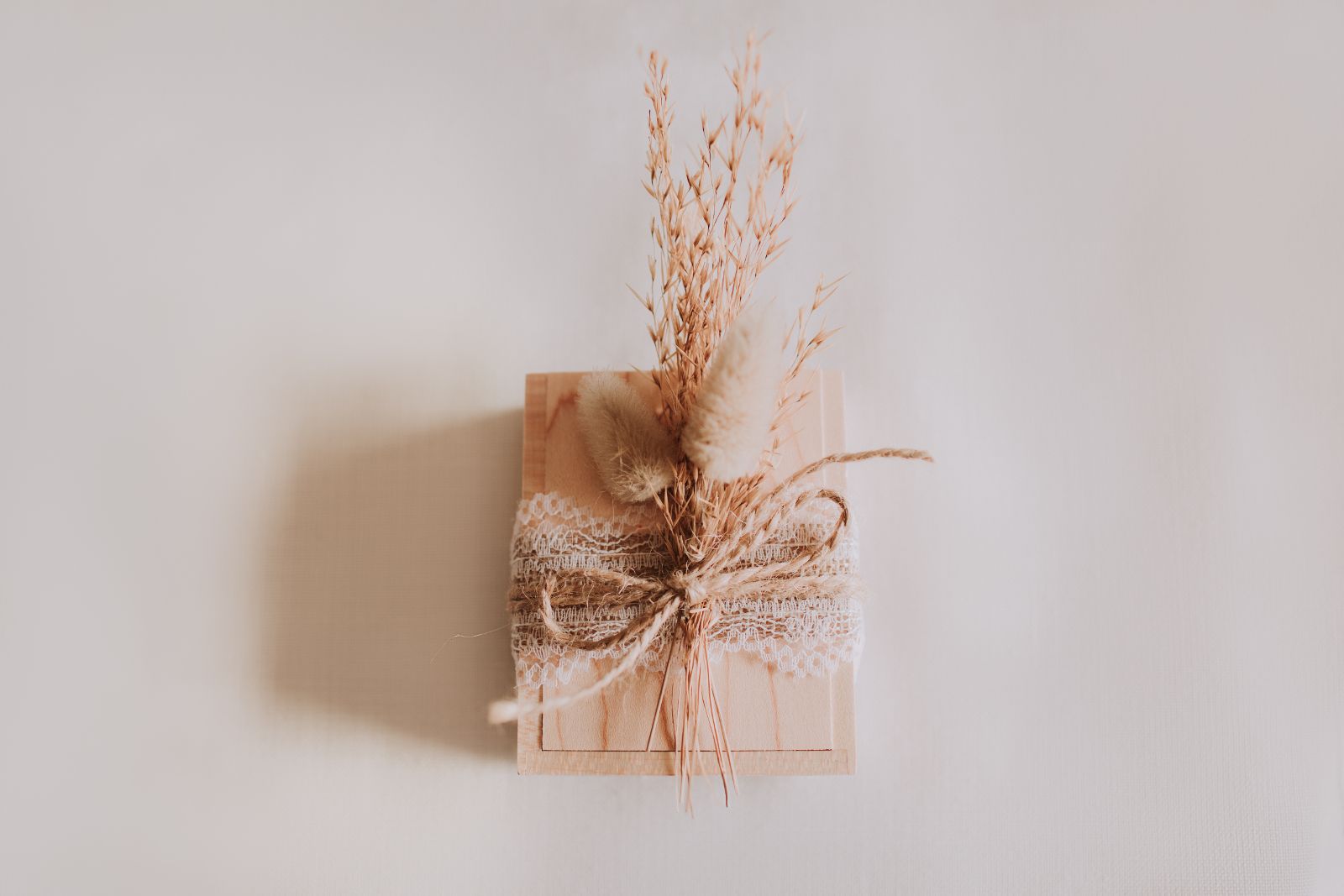 Scatola di legno con la chiavetta USB vista dall'alto, decorata con pizzo, spago e fiori secchi