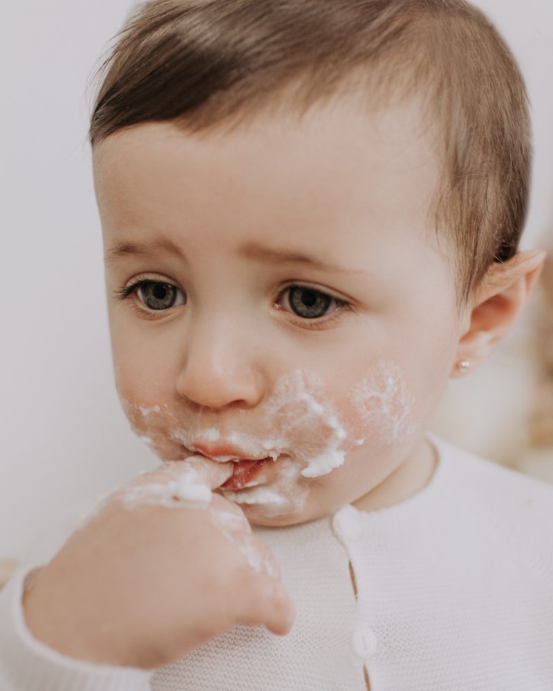 Bambina che assaggia la torta con le mani durante una sessione Smash Cake
