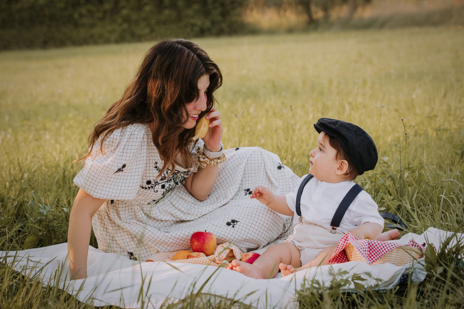 Mamma con un vestito a fiori e il suo bambino durante un picnic in un prato
