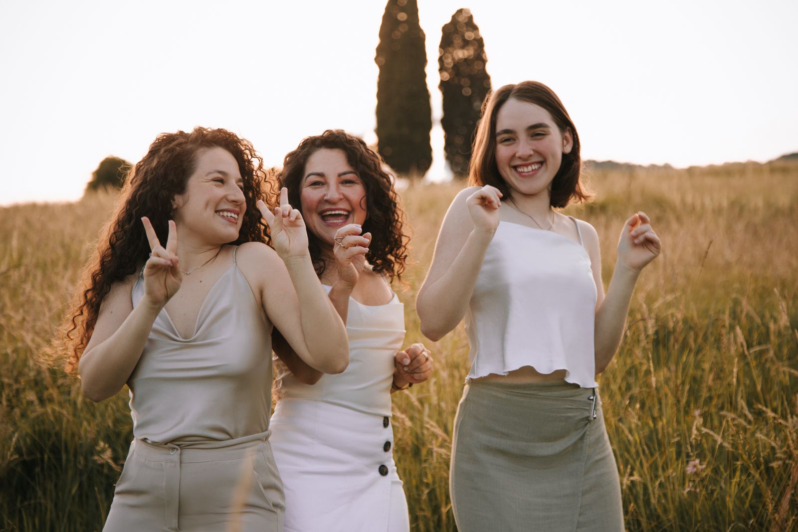 Tre ragazze che ridono insieme in un campo al tramonto