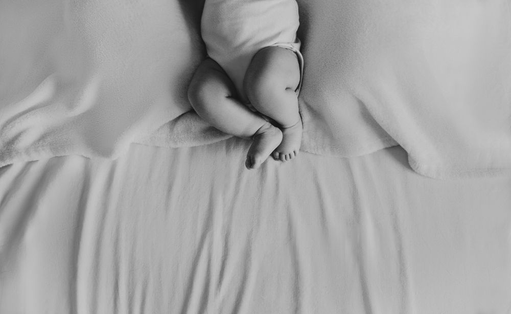Neonato addormentato su una coperta bianca durante una sessione newborn a domicilio a Bergamo