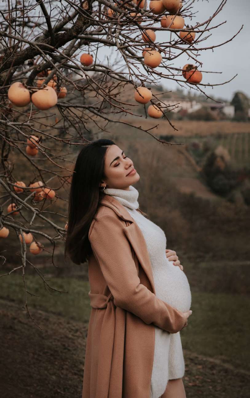 Donna in attesa che accarezza il pancione all'aperto