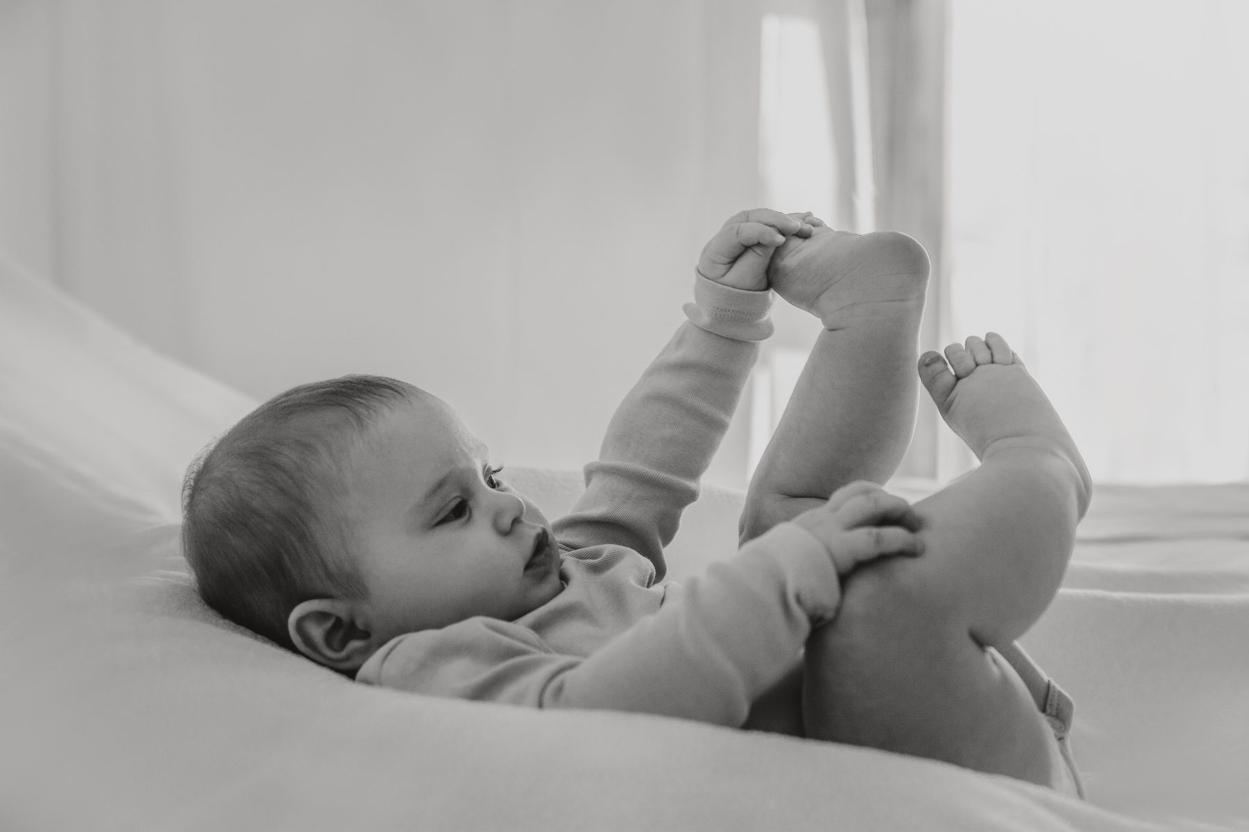 Neonato sdraiato che gioca con i suoi piedini