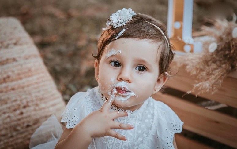 Bambina che assaggia la crema della torta con le mani