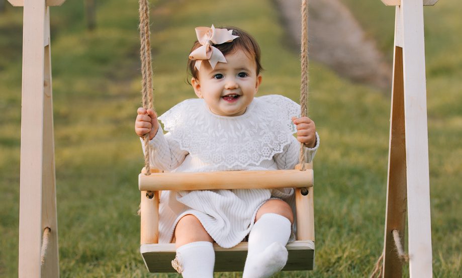 Bambina in abito bianco seduta sulla coperta del set fotografico